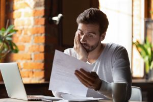 Worker puzzles through forms at his desk.